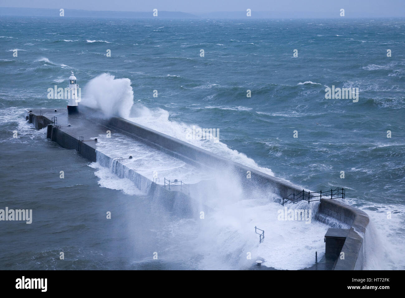 Harbour wall and lighthouse beaten by rough waves at Mevagissey in Cornwall, UK. Stock Photo