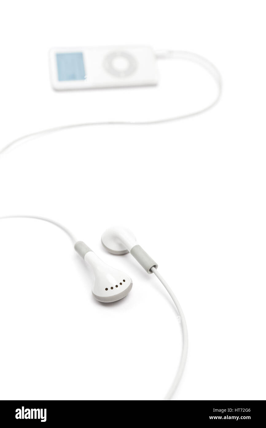 Bath, United Kingdom - March 11, 2011: Studio shot of white earbuds with an Apple iPod Nano out of focus in the background. Stock Photo