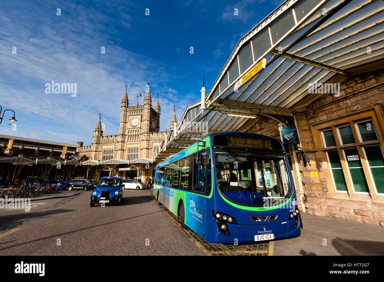 BRISTOL, UK - March 14, 2011: Exterior of Bristol Temple Meads Railway Station with a stationary Bristol Airport Shuttle Bus and passing Taxi Stock Photo