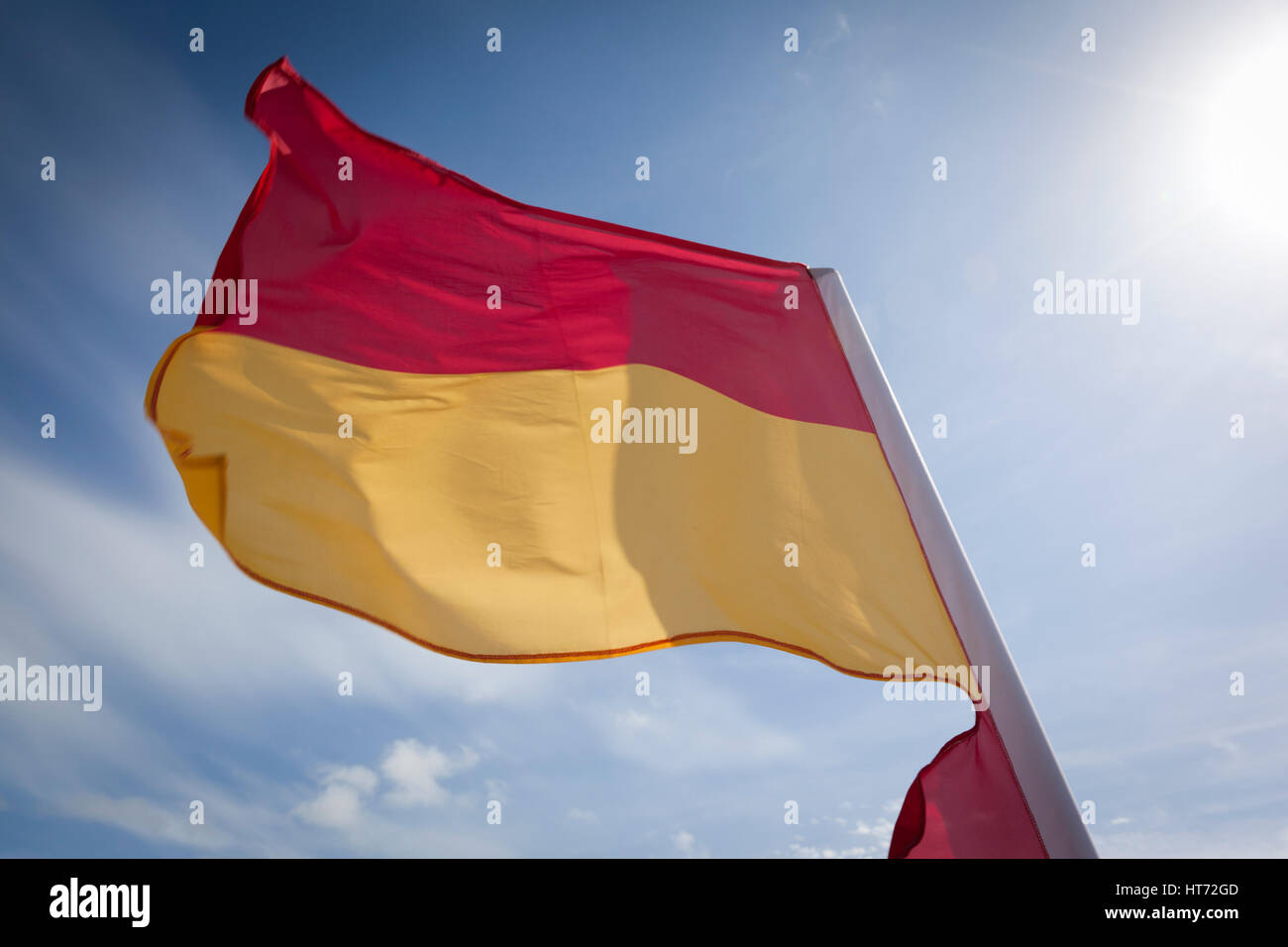 WOOLACOMBE, UK - MAY 19: A red and yellow safety flag fluttering in the wind against a bright blue sky at Woolacombe beach on 19th May 2011. The flag  Stock Photo
