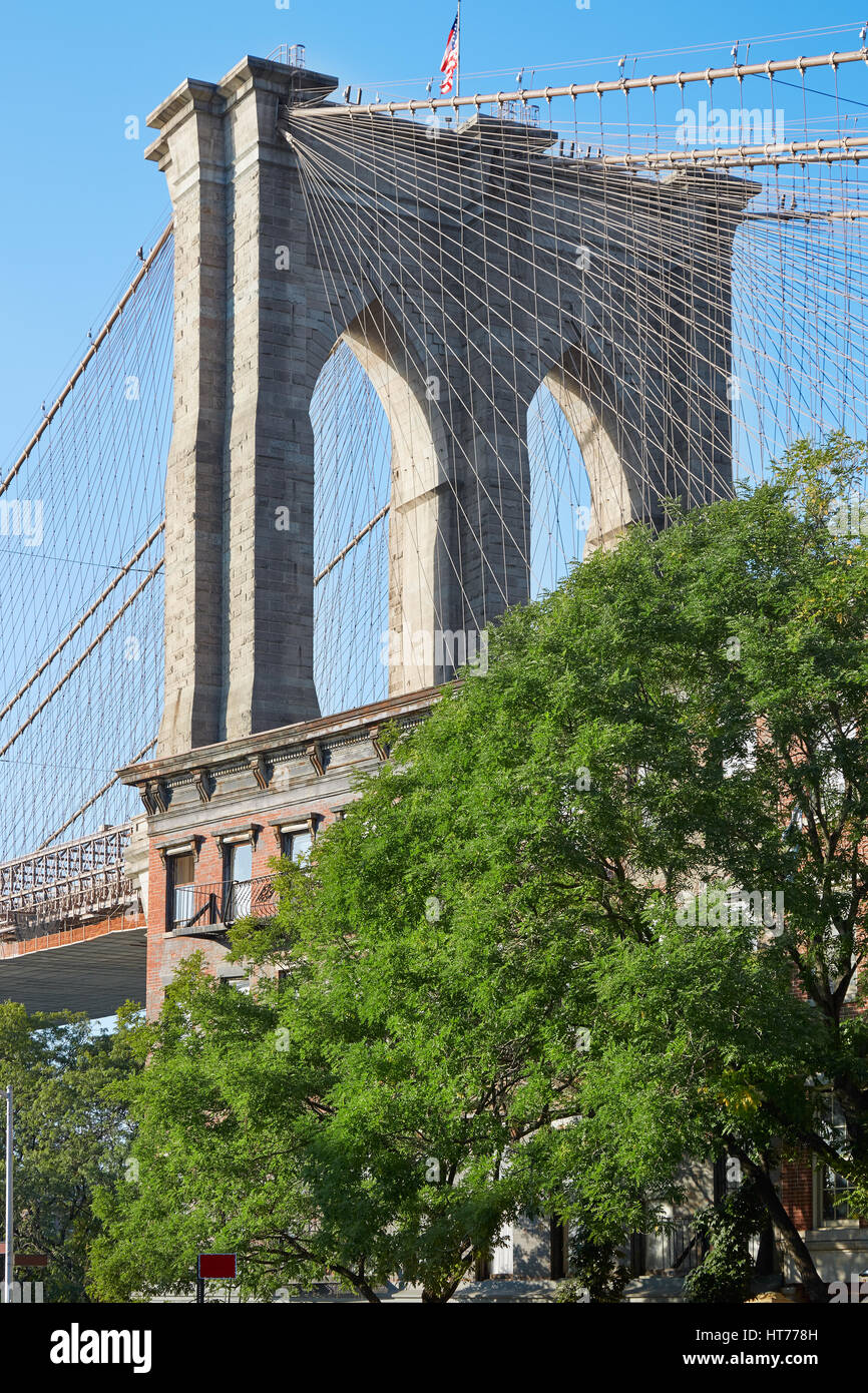 Brooklyn Bridge pillar and green trees in New York, sunny day Stock Photo