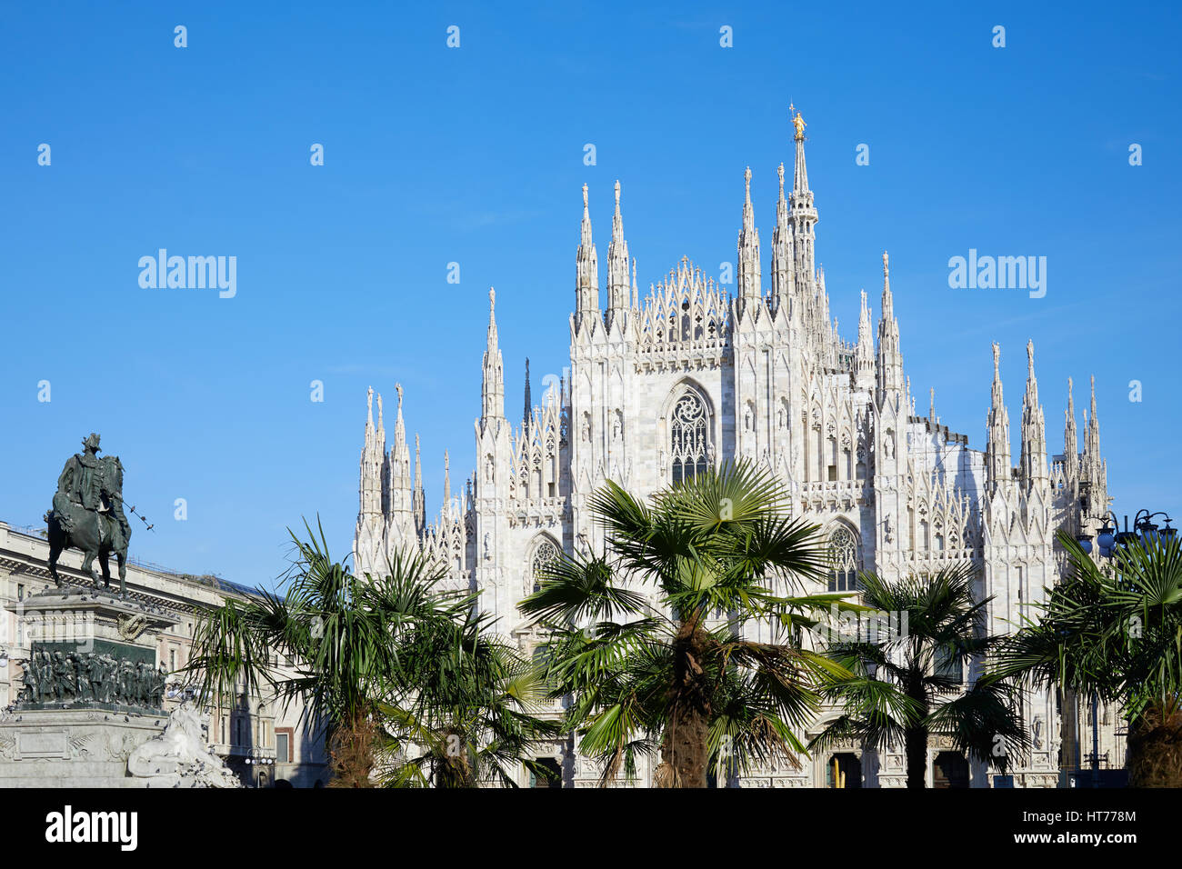 Milan Duomo cathedral with palm trees, blue sky in a sunny day Stock Photo