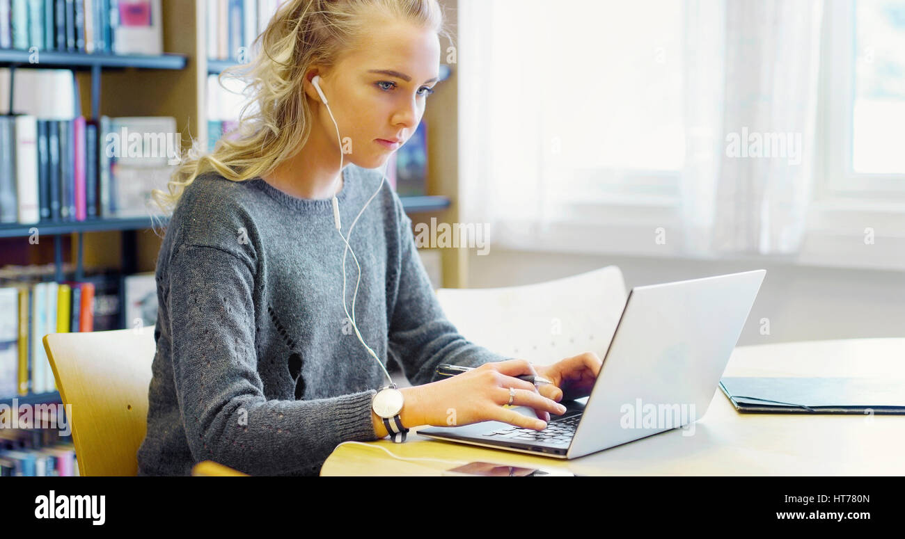 Hardworking female student working on laptop in the library Stock Photo
