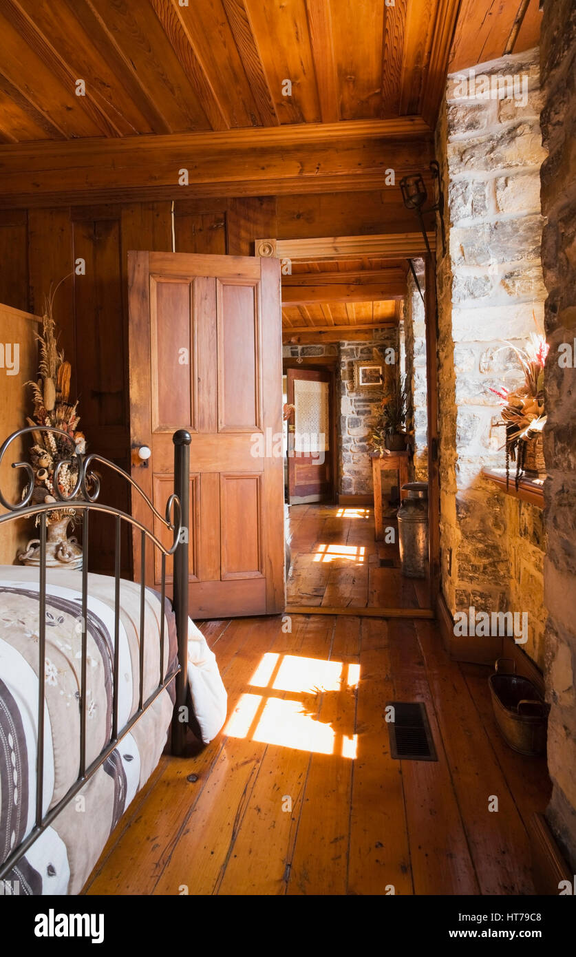 Master bedroom with antique bed and opened door in 1750 old house