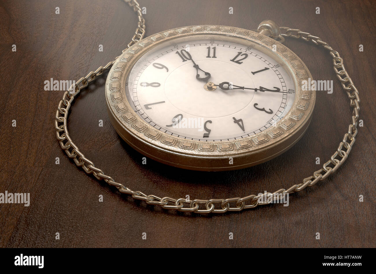 A closeup of an intricate gold antique pocket watch attached to a chain on a wooden surface background - 3D render Stock Photo
