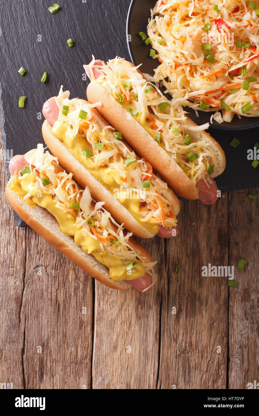 Hot dog with sauerkraut and mustard close up on the table. Vertical view from above Stock Photo