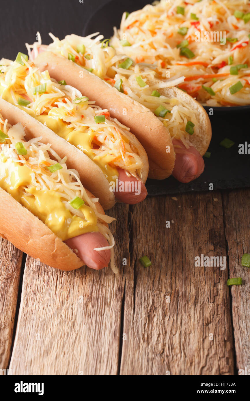 Hot dog with sauerkraut and mustard close up on the table. vertical Stock Photo