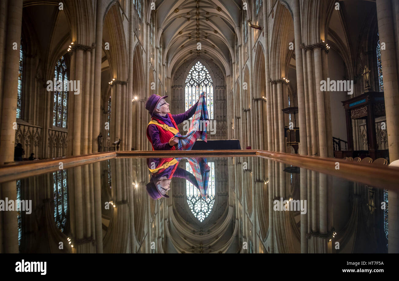 International Women&acirc;€™s Day is celebrated at York Minster as Issy Sanderson holds material used to make feminine hygiene kits for girls in developing countries, while being reflected in a mirror used by visitors to view the ceiling of the Minister. Stock Photo