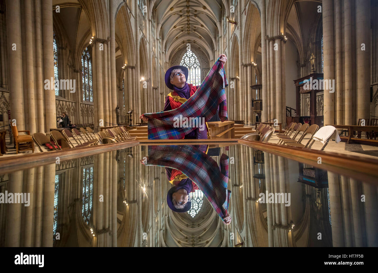International Women&acirc;€™s Day is celebrated at York Minster as Issy Sanderson holds material used to make feminine hygiene kits for girls in developing countries, while being reflected in a mirror used by visitors to view the ceiling of the Minister. Stock Photo