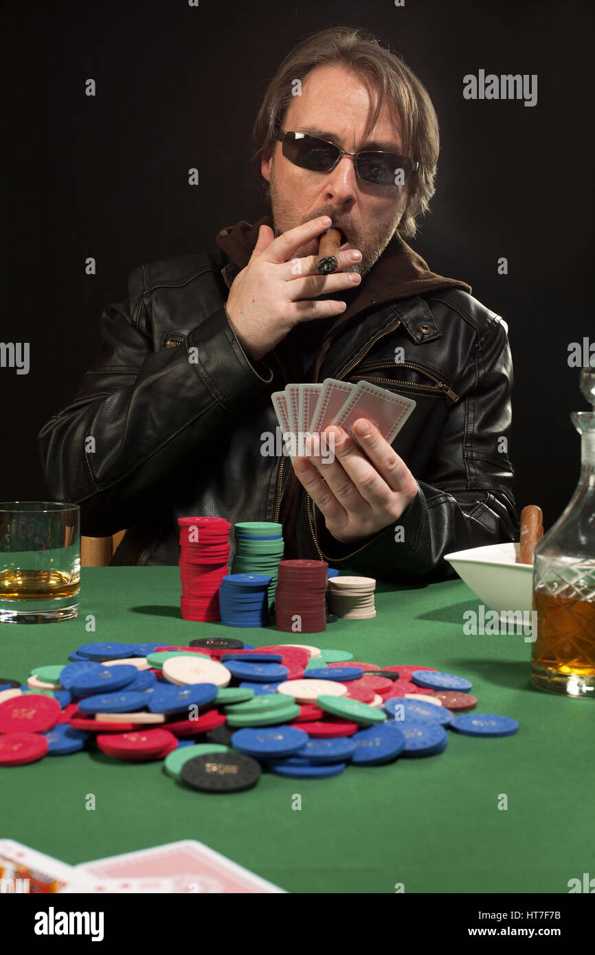 Photo of a man playing poker while wearing sunglasses and smoking a