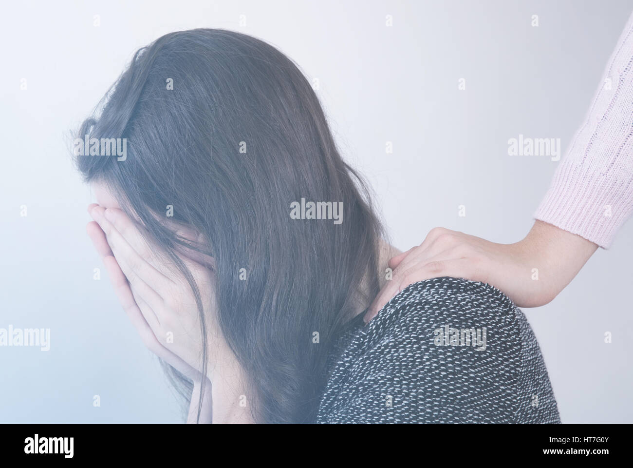 depressed teenage girl covering her face and a hand offering help Stock Photo