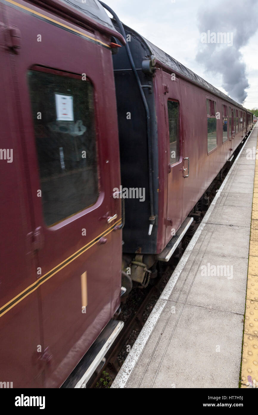 Old steam train with railway carriages in British Railways colours arriving at a station platform. Nottingham Heritage Transport Centre, England, UK Stock Photo