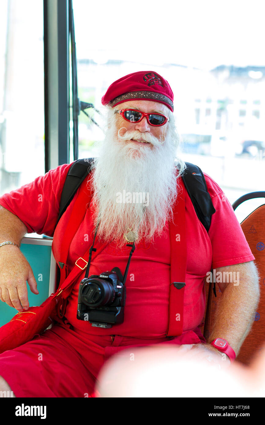 Helsinki, Finland - August 5, 2012: American Santa Claus in red summer suit with photo camera sitting in tram car. Stylish interior tram with comforta Stock Photo