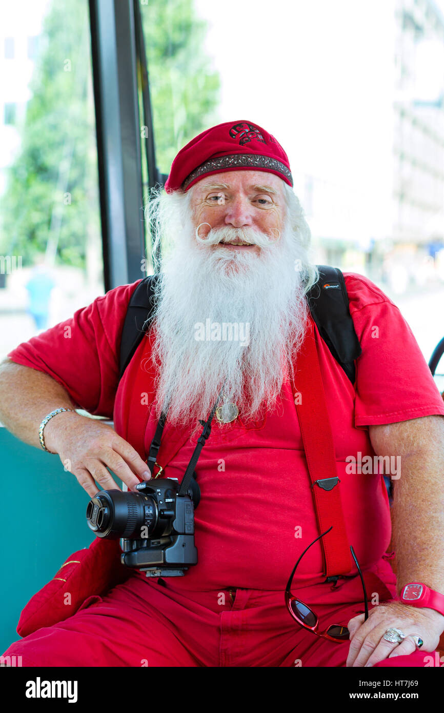 Helsinki, Finland - August 5, 2012: American Santa Claus in red summer suit with photo camera sitting in tram car. Stylish interior tram with comforta Stock Photo