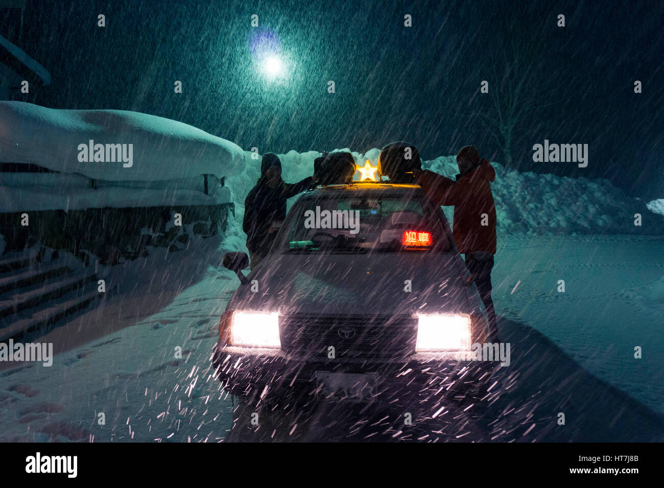 Snowboarders Unloading Gear From Top Of Taxi Car In Asahidake, Japan Stock Photo