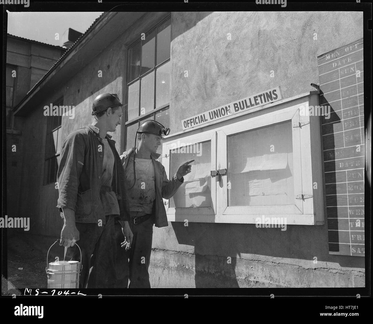 Photograph of two Union Pacific Coal Company miners reading notices on a bulletin board, Reliance, Wyoming, July 9, 1946. Image courtesy Russell Lee/US National Archives. Stock Photo