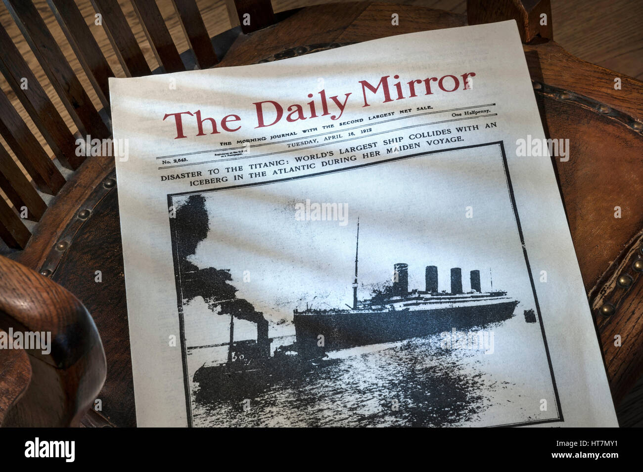 TITANIC NEWSPAPER Daily Mirror dated April 16th 1912, with RMS Titanic ship disaster headline, on old bosuns chair lit by shaft of window light Stock Photo