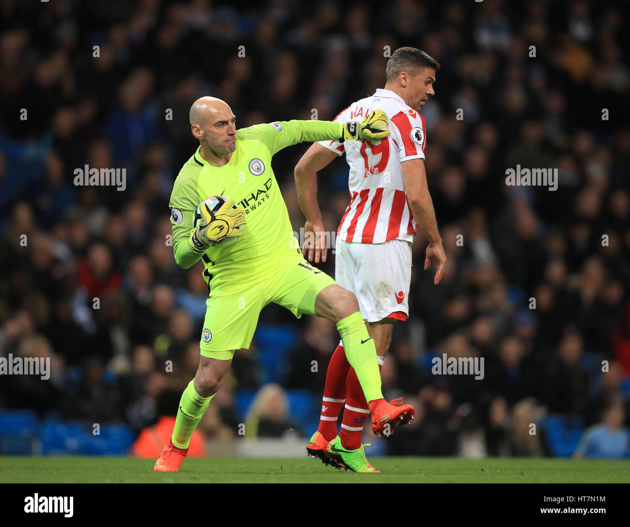 Stoke City's Jonathan Walters (right) and Manchester City goalkeeper Willy Caballero during the Premier League match at the Etihad Stadium, Manchester. Stock Photo