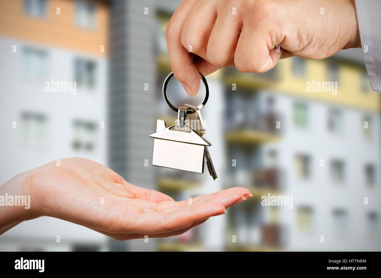 Man gives a woman the keys to a new home. Chrome pedant with house shape Stock Photo
