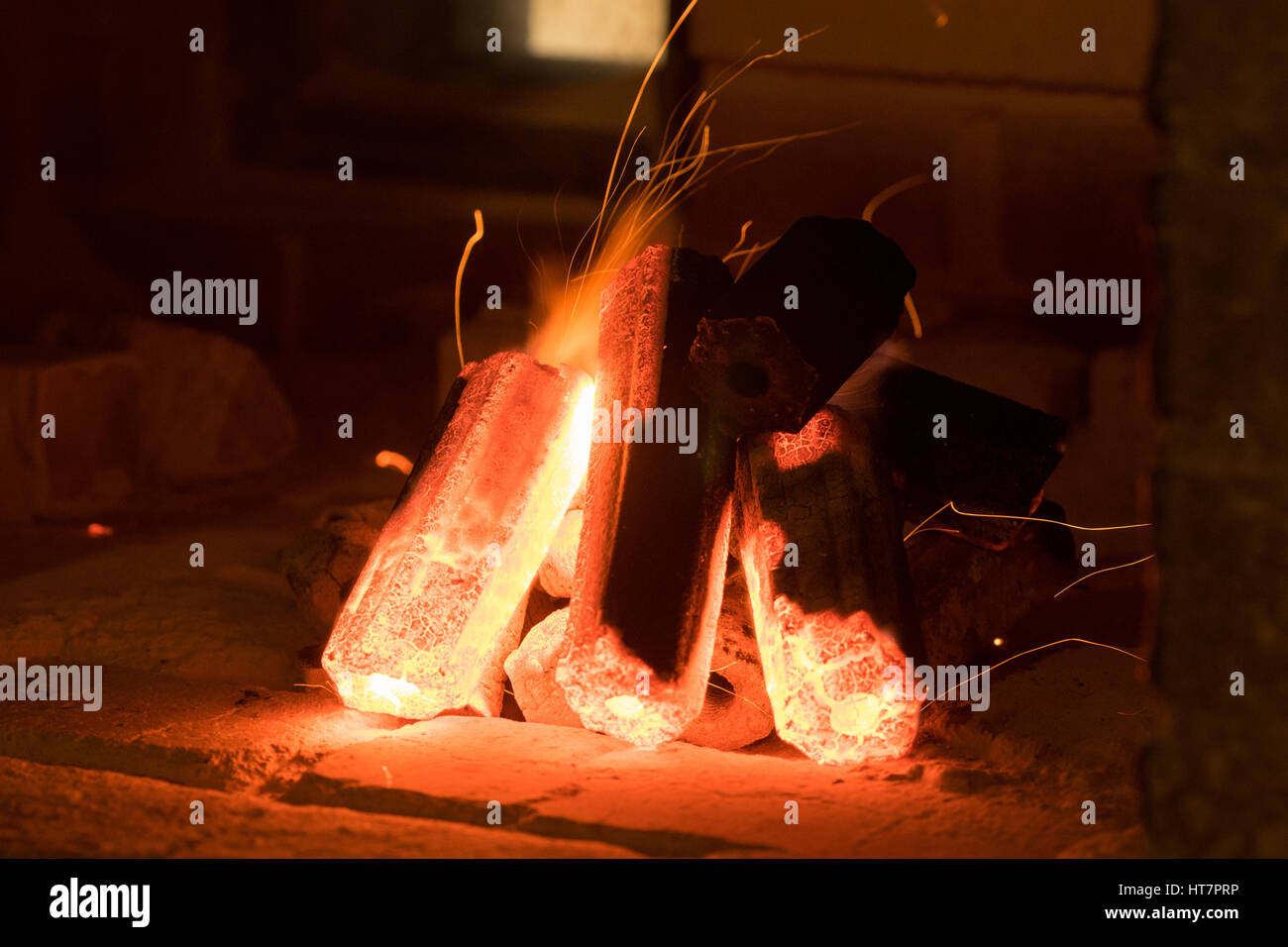 Activated charcoal burning inside a stove in preparation for grilling