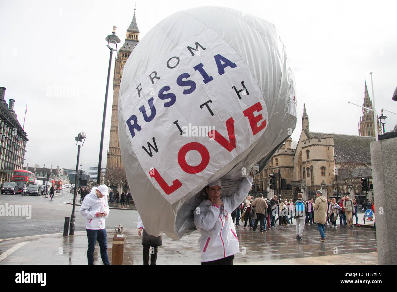 London, UK. 8th Mar, 2017. A group of men inflate a balloon with the inscription 'From Russia With Love Make Her Smile' hand out flowers outside Parliament to celebate International Women's Day Credit: amer ghazzal/Alamy Live News Stock Photo
