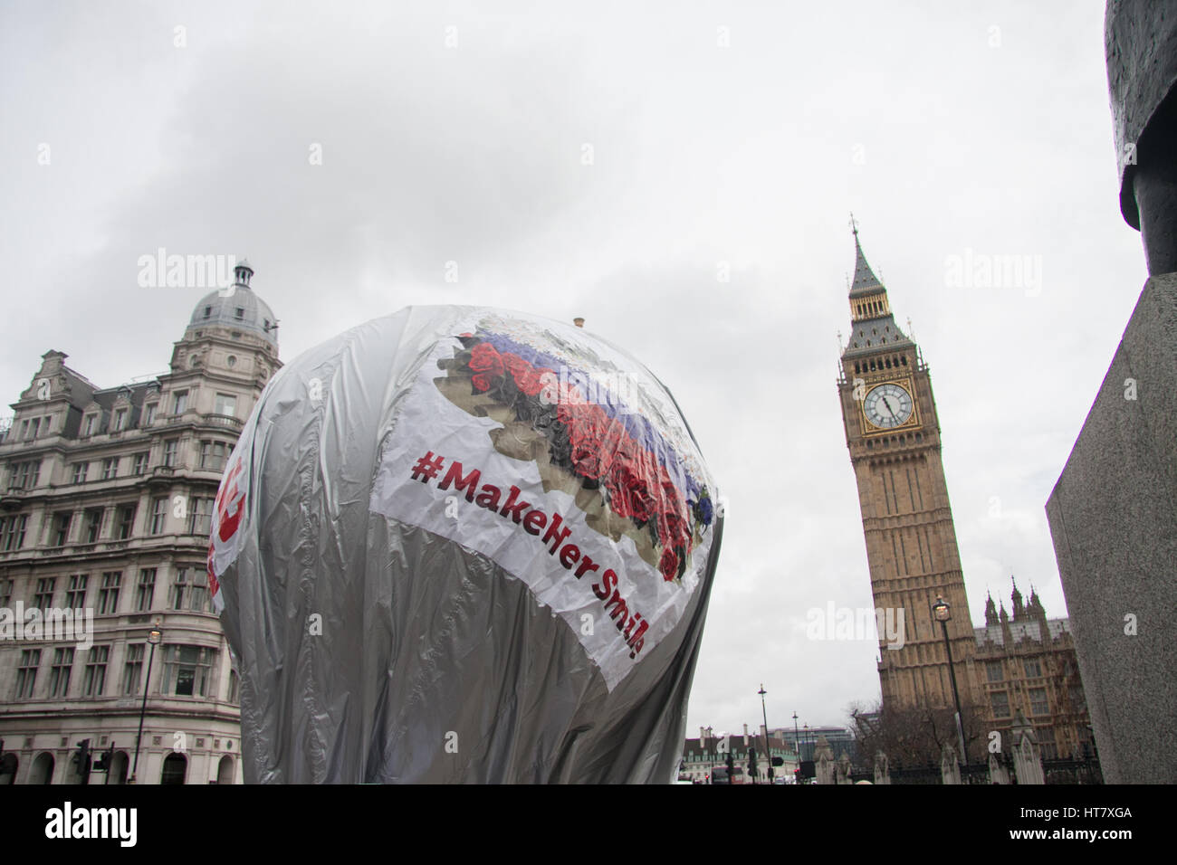 A group of men inflate a balloon with the inscription 'From Russia With Love Make Her Smile' hand out flowers outside Parliament to celebate International Women's Day Credit: amer ghazzal/Alamy Live News Stock Photo