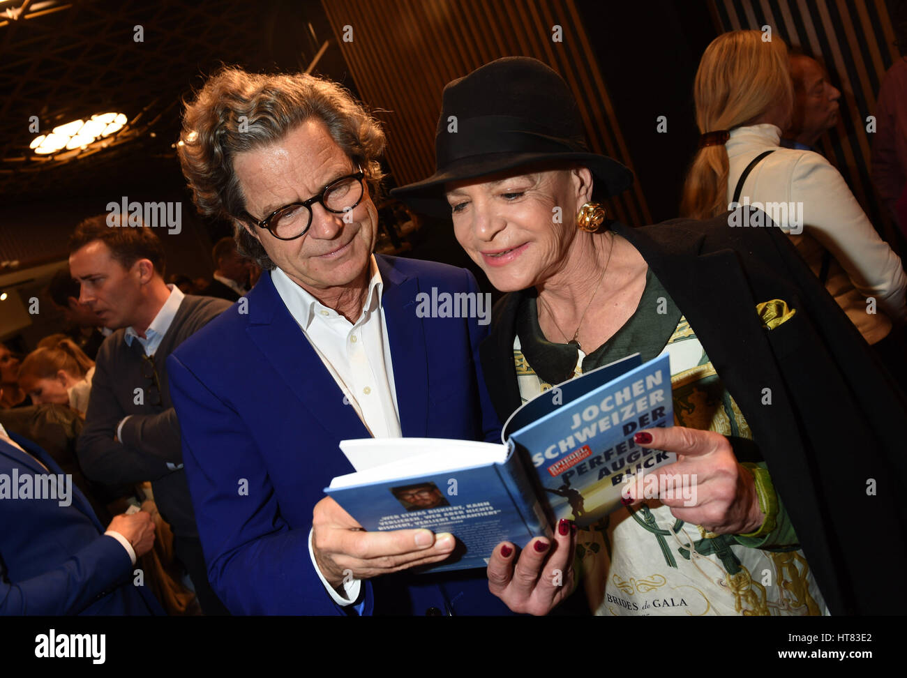 Taufkirchen, Germany. 08th Mar, 2017. Publisher Florian Langenscheidt and designer Barbara Engel holding a book by Jochen Schweizer at the so-called red carpet opening of a theme park at the Jochen Schweizer Arena in Taufkirchen, Germany, 08 March 2017. Photo: Felix Hörhager/dpa/Alamy Live News Stock Photo
