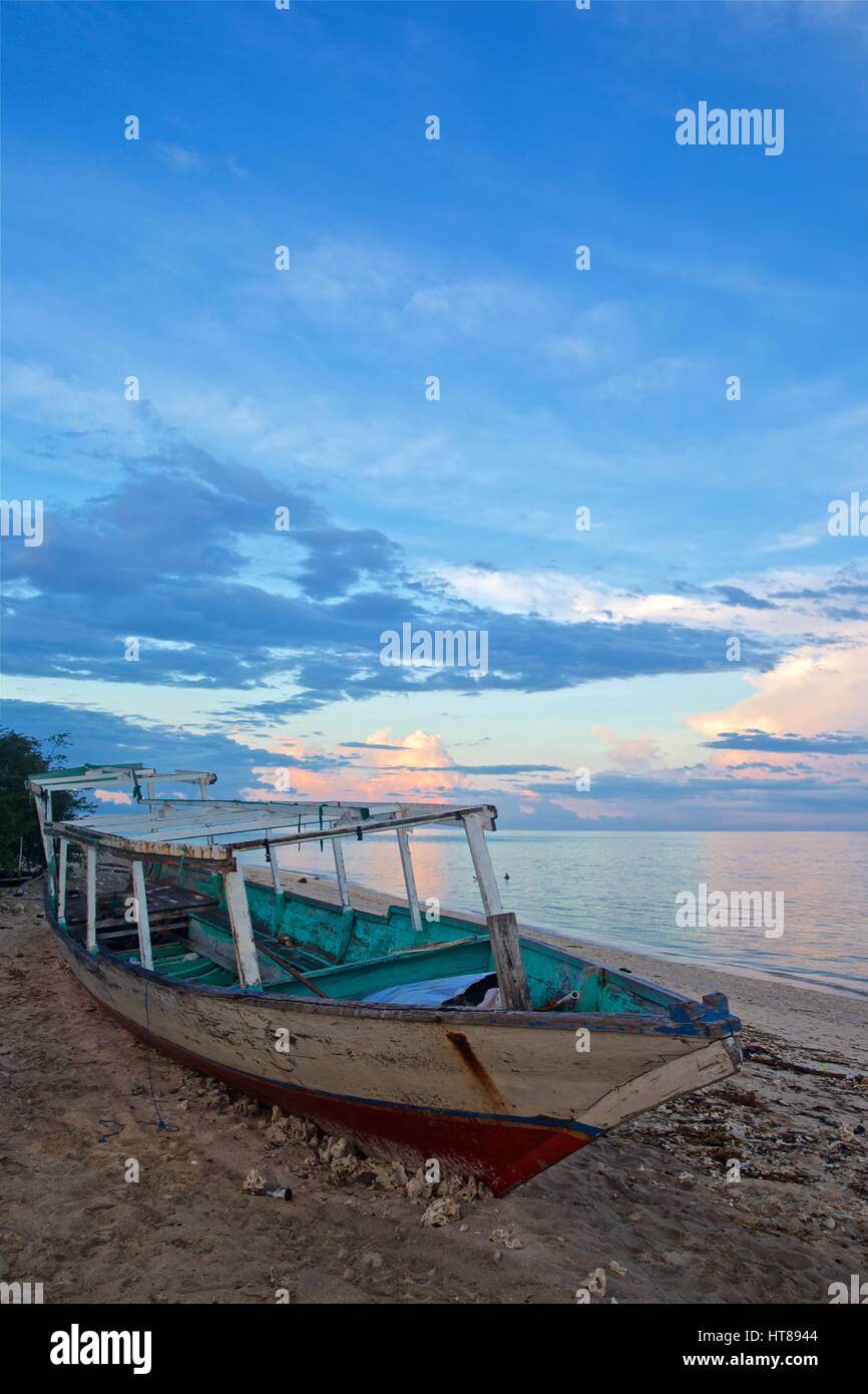 Traditional wooden boat abandoned on beach at sunset Stock Photo