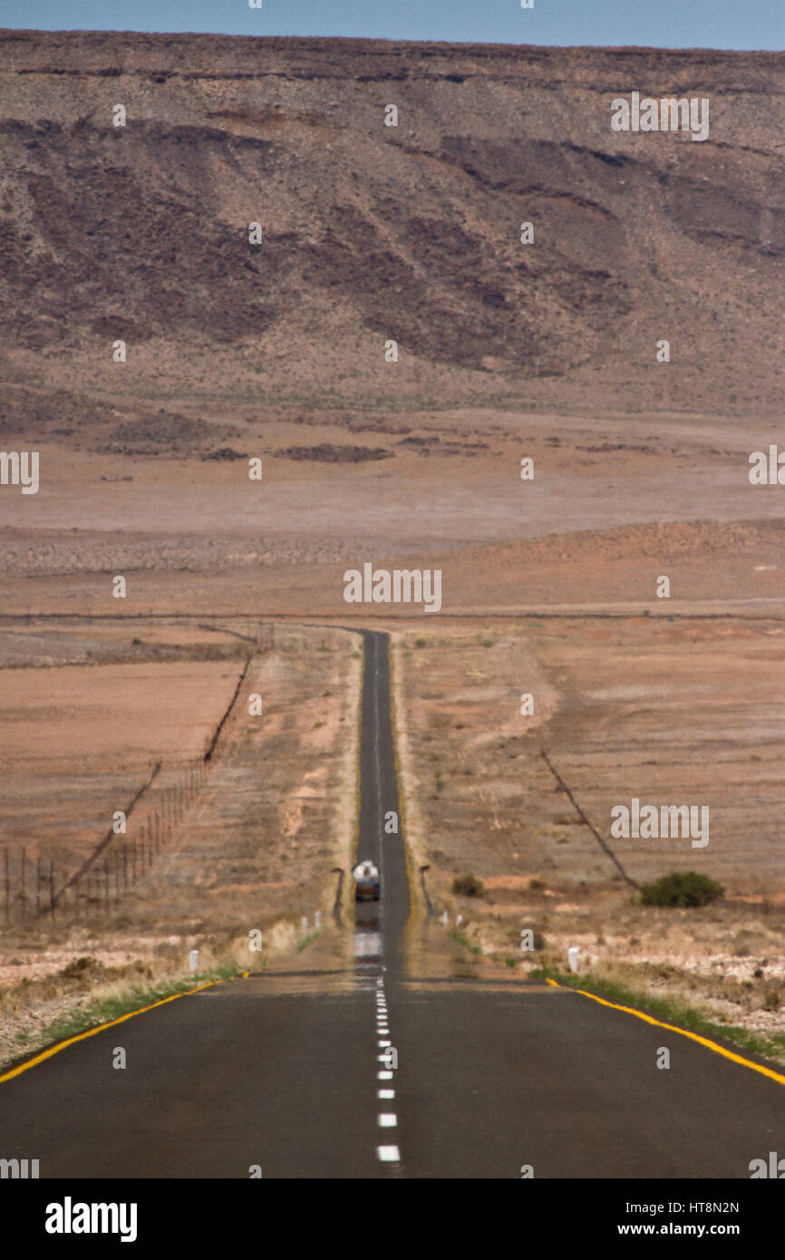 A long straight road heading downhill towards the mountains in Namibia Stock Photo