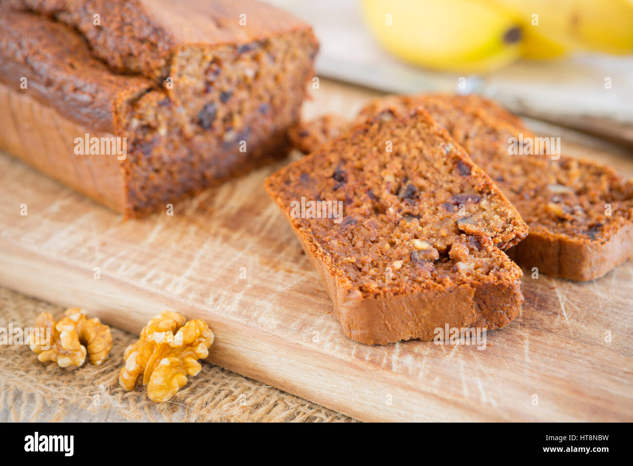 Homemade banana bread with walnuts and dates on a rustic table. Stock Photo