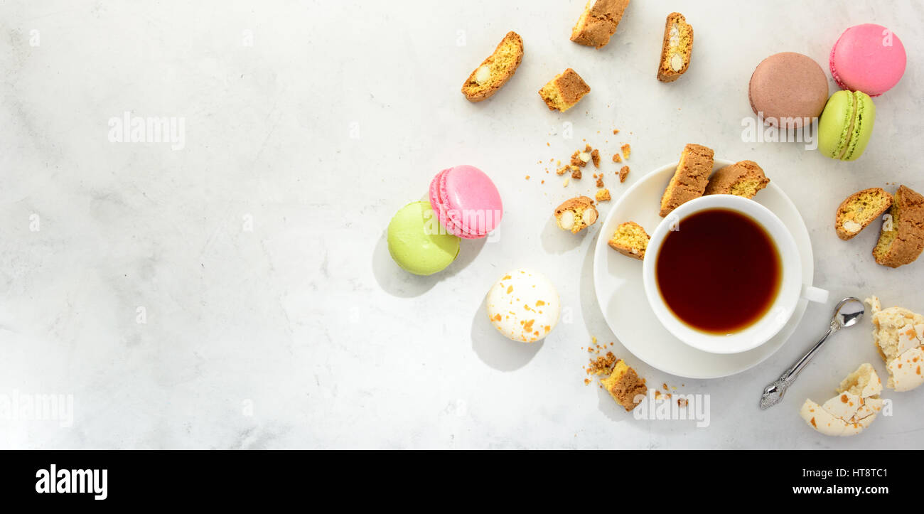 Cup of black tea with tasty almond cookies, rich in vitamins, minerals and varicolored macaroons  on a white background in light key. Top view , copy  Stock Photo