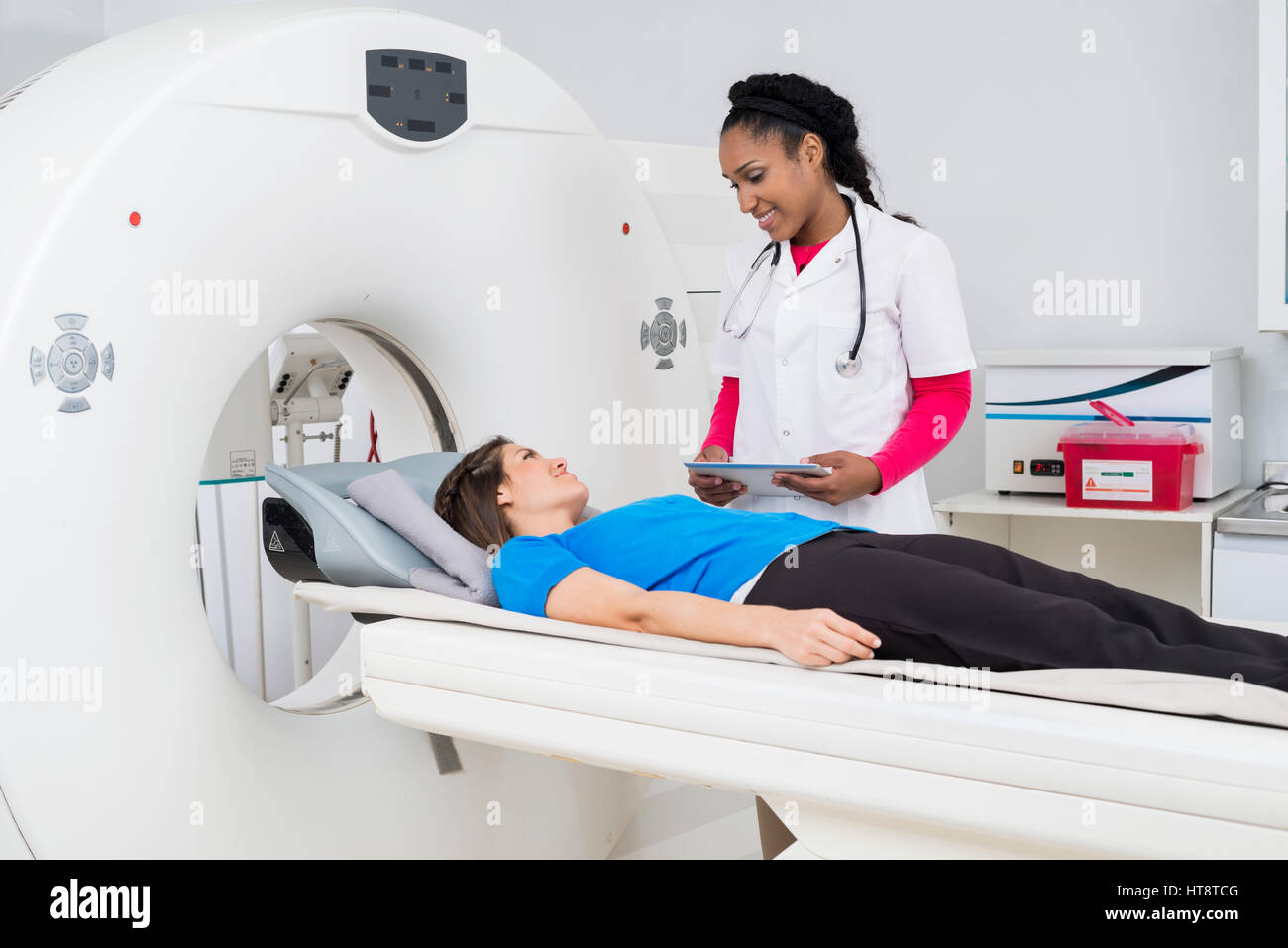 Young female doctor looking at patient undergoing MRI scan at hospital ...