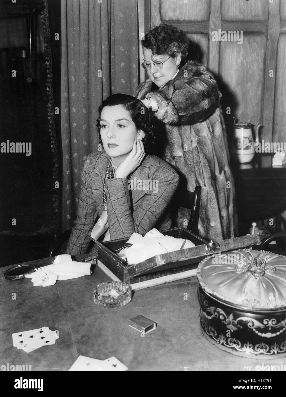'Here's a candid peek at Rosalind Russell between scenes on Metro-Goldwyn-Mayer's 'Night Must Fall' set. Robert Montgomery is starred in this weird mystery drama, under the direction of Richard Thorpe.' Stock Photo