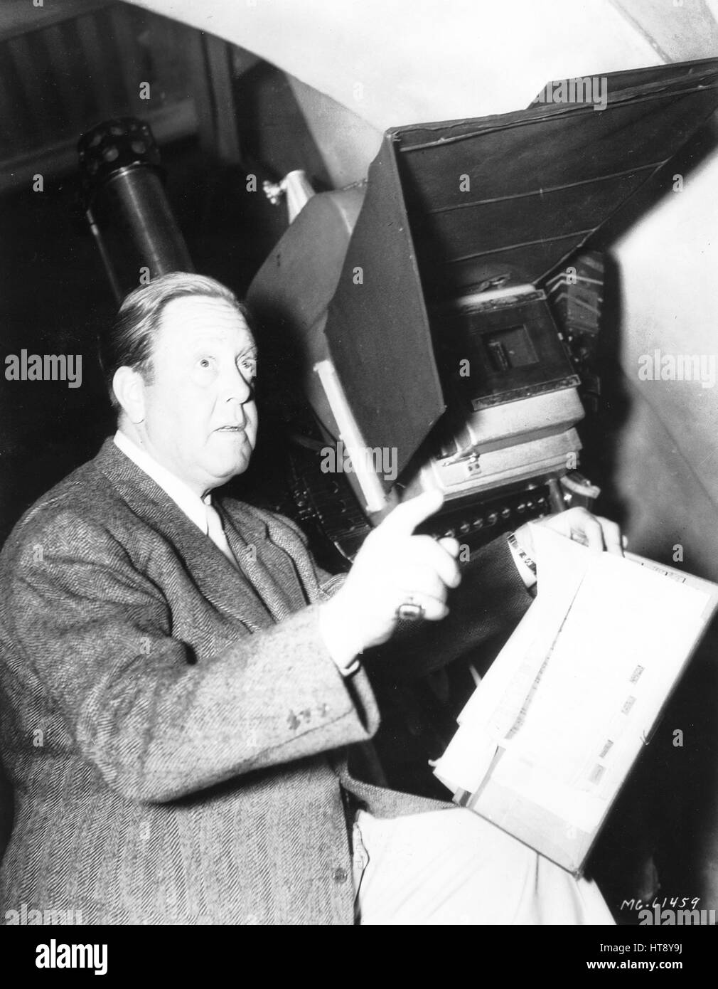 'The candid cameraman has caught some of Hollywood's most famous directors at work. Director Robert Z. Leonard, once a singer himself, absent-mindedly beats time as Jeanette MacDonald and Allan Jones sing in Rudolf Friml's 'The Firefly' on an M-G-M sound stage.' Stock Photo