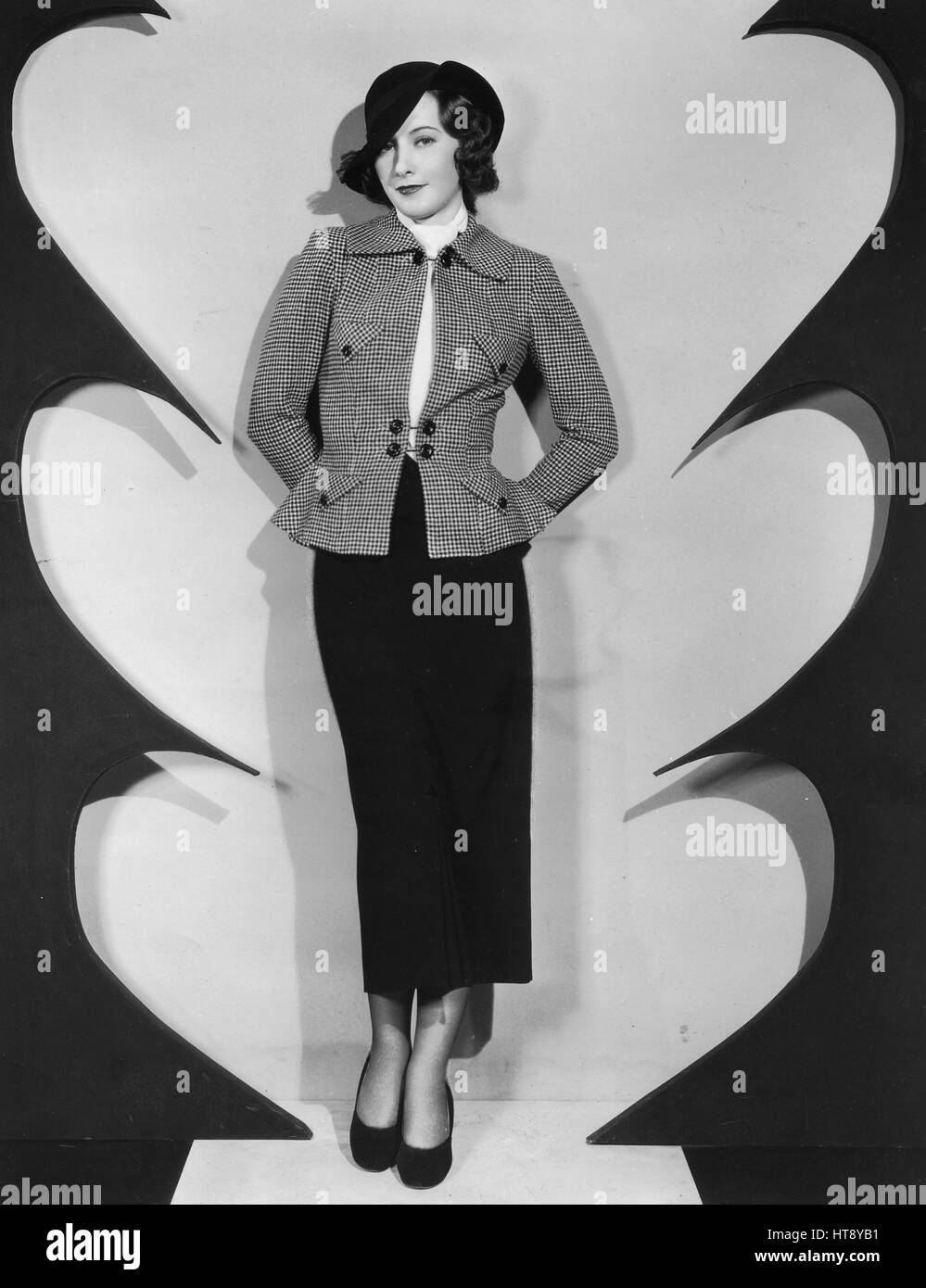 'Checks are smart for sports: Barbara Stanwyck sponsors this ultra smart checked jacket worn with a dark skirt and felt hat in her next Warner picture, 'A Lost Lady.'' Stock Photo