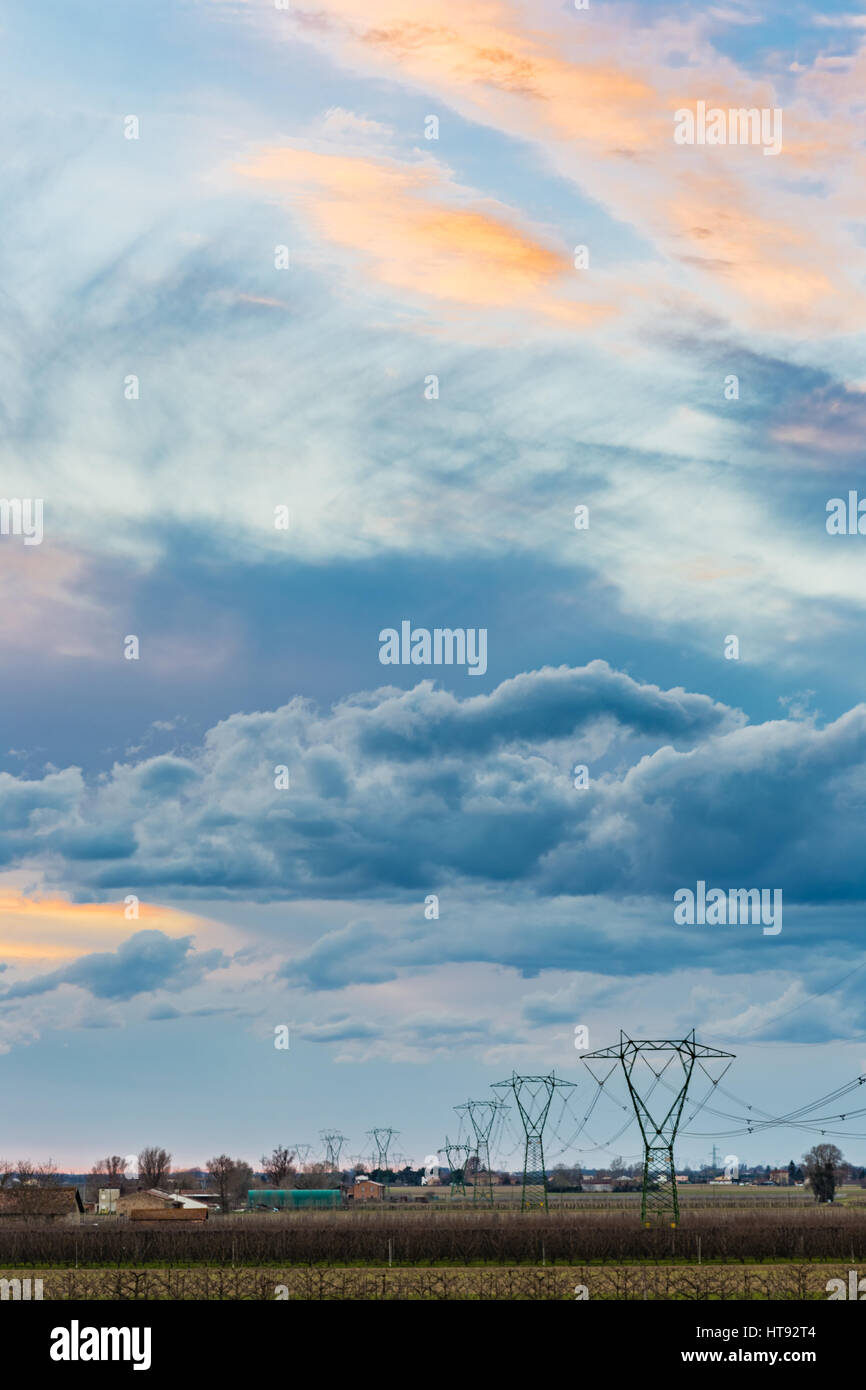 High voltage electricity pylons and power line in cultivated fields at