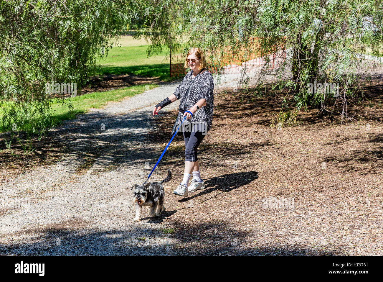 A woman walks her dog on leash at Bicentennial Park, Sunbury, Vic