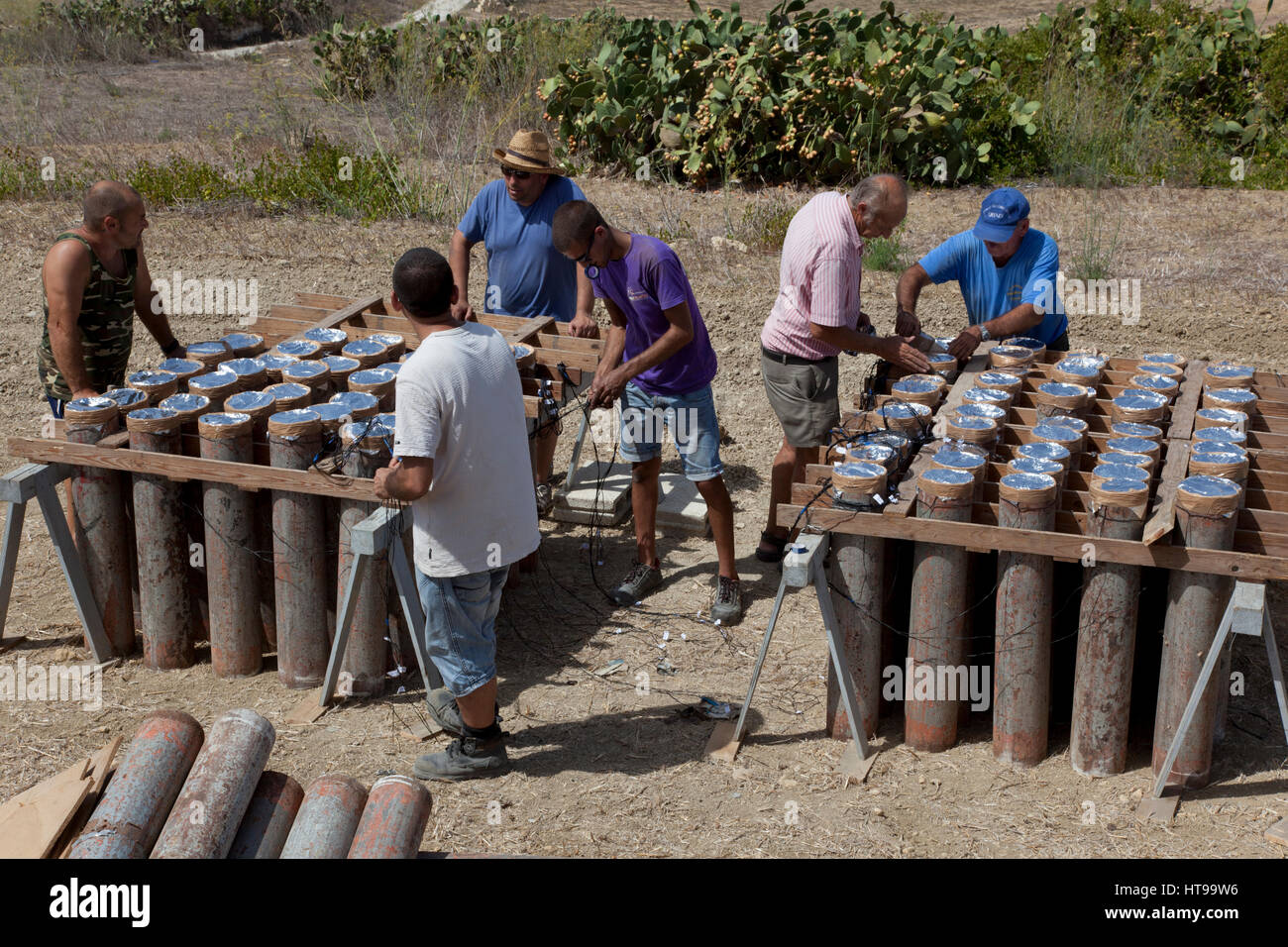 Maltese pyrotechnicians setting the fireworks in launch tubes at the launch site of a fireworks show set up for one of the town feasts in Malta. Stock Photo