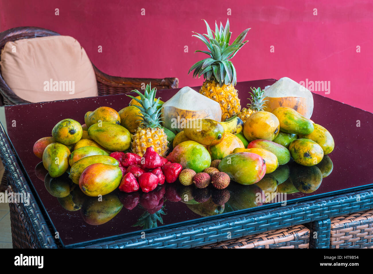 Fresh tropical Mauritius fruits on a purple glass table in the magenta background. The selection