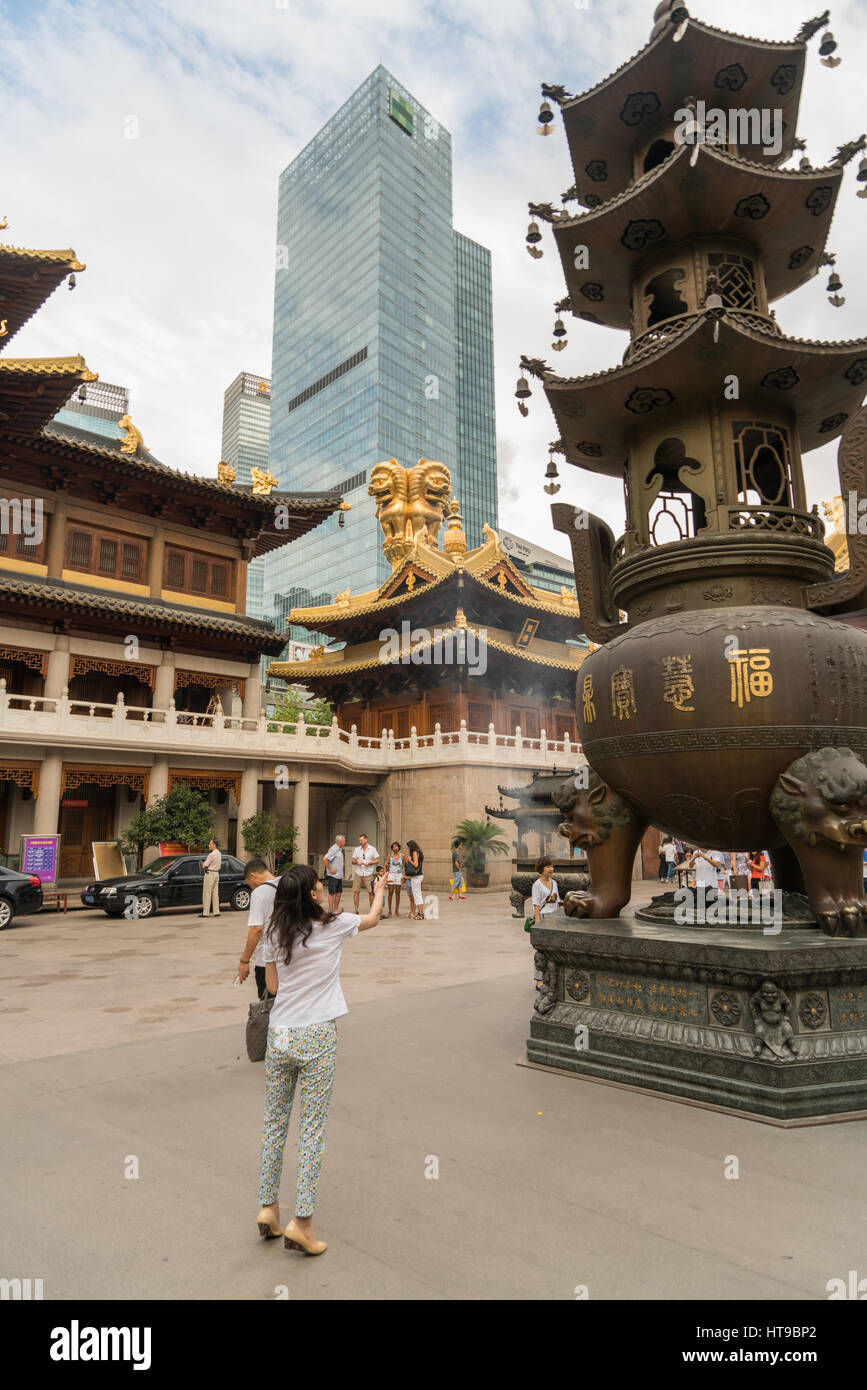 A woman throws coins into a bronze statue for good luck at a Buddhist