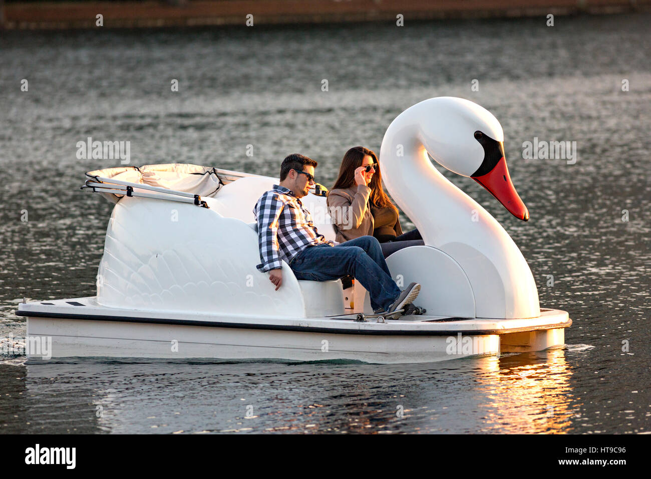 A couple paddle a Swan boat around Lake Eola Park in Orlando, Florida