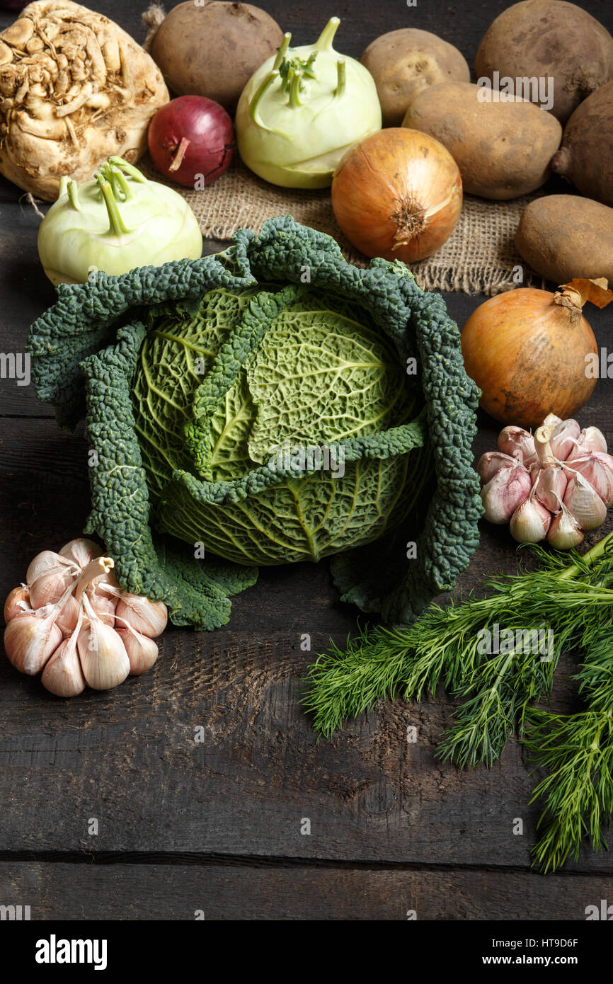 Spring vegetables on a dark background: Savoy cabbage, cauliflower, onion, garlic, kohlrabi, celery root, dill. Top view Lay flat Stock Photo