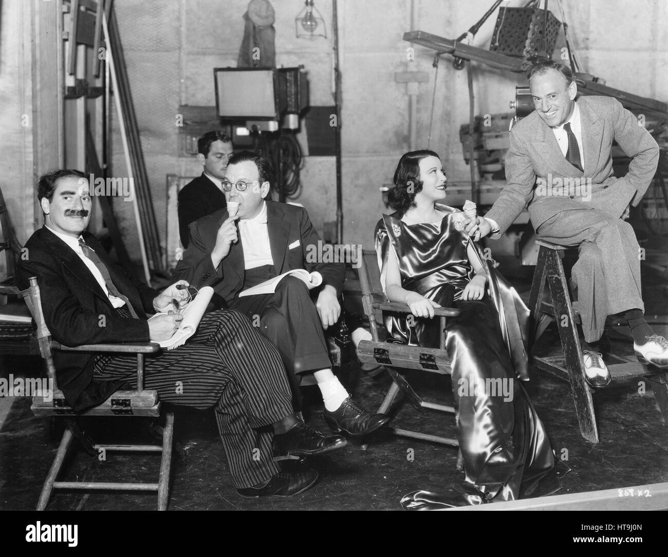 'A refreshing picture...The Marx Brothers made things so hot during the filming of scenes for 'A Night at the Opera,' their new starring comedy now in production at the Metro-Goldwyn-Mayer studios, that director Sam Wood called for ice cream cones. Groucho Marx, Al Boasberg, gag man; Kitty Carlisle, leading lady, and Director Wood are in the picture.' Stock Photo