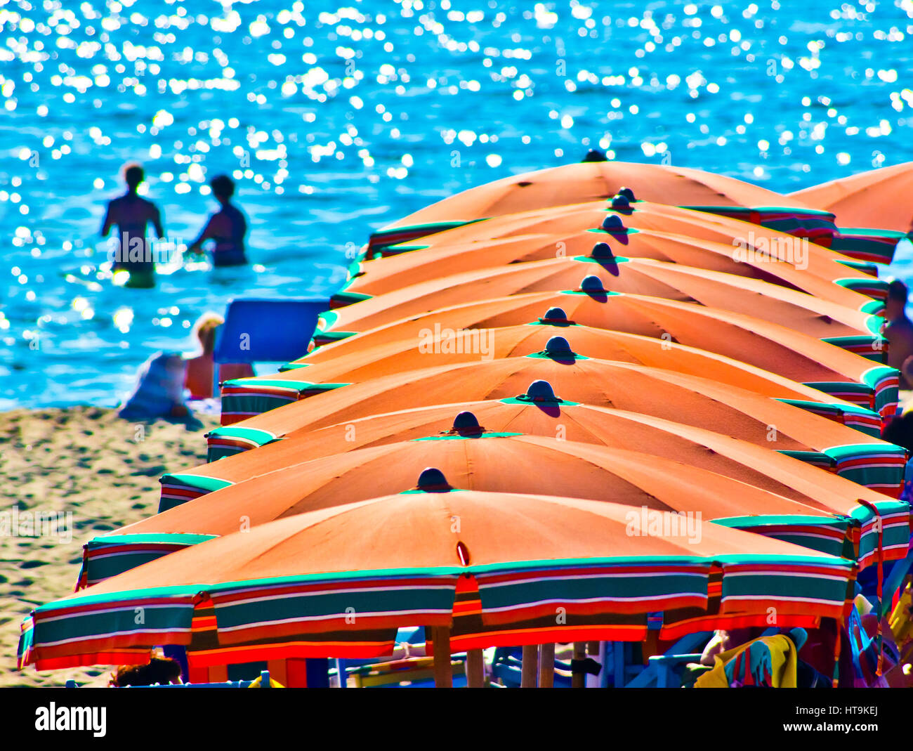 bathers on vacation on the sea background with orange umbrellas in summer with blue sky Stock Photo