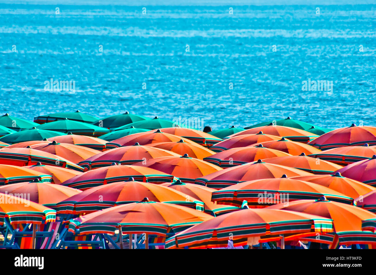 orange umbrellas in summer with blue sea in the background Stock Photo