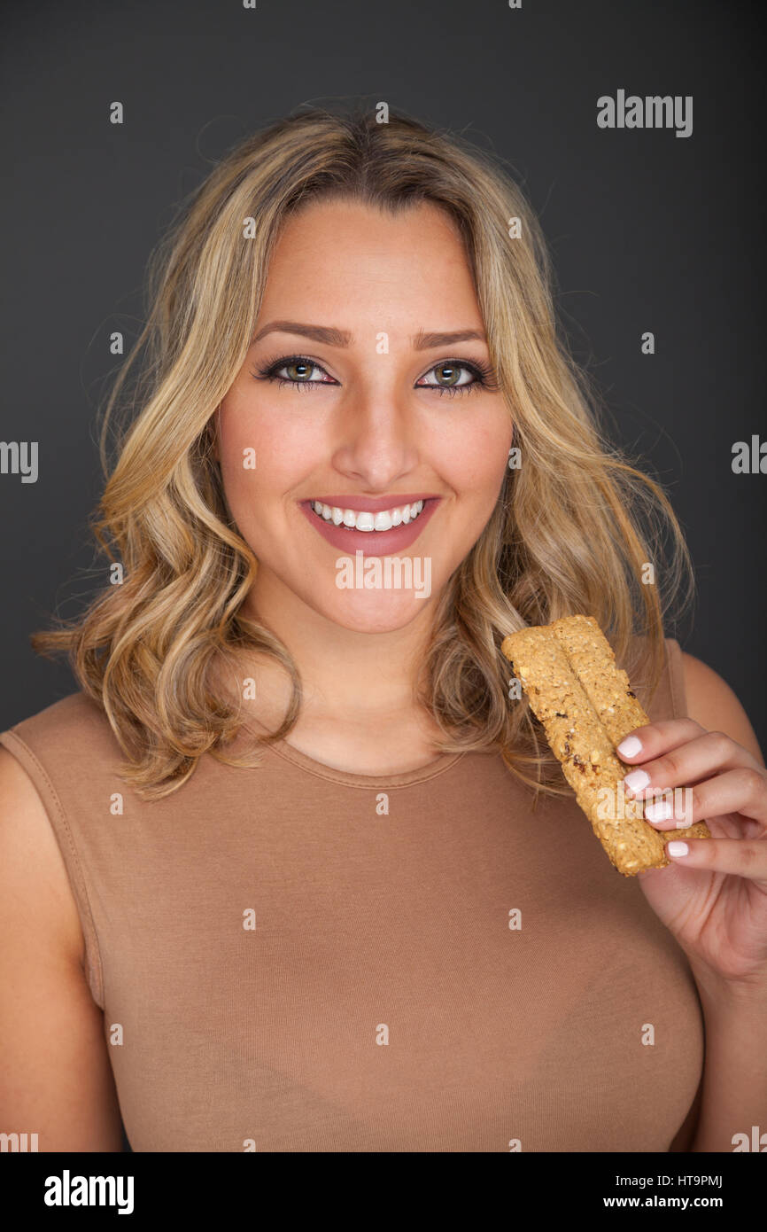 Pretty blonde woman standing holding a breakfast cereal bar. Stock Photo