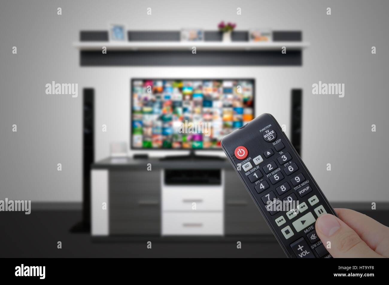 Watching television in modern TV room. Hand holding remote control Stock Photo