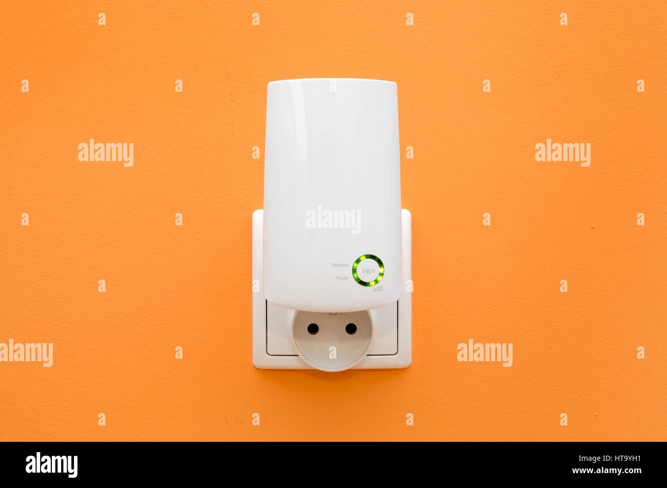 WiFi repeater in electrical socket on orange wall. Simply way to extend