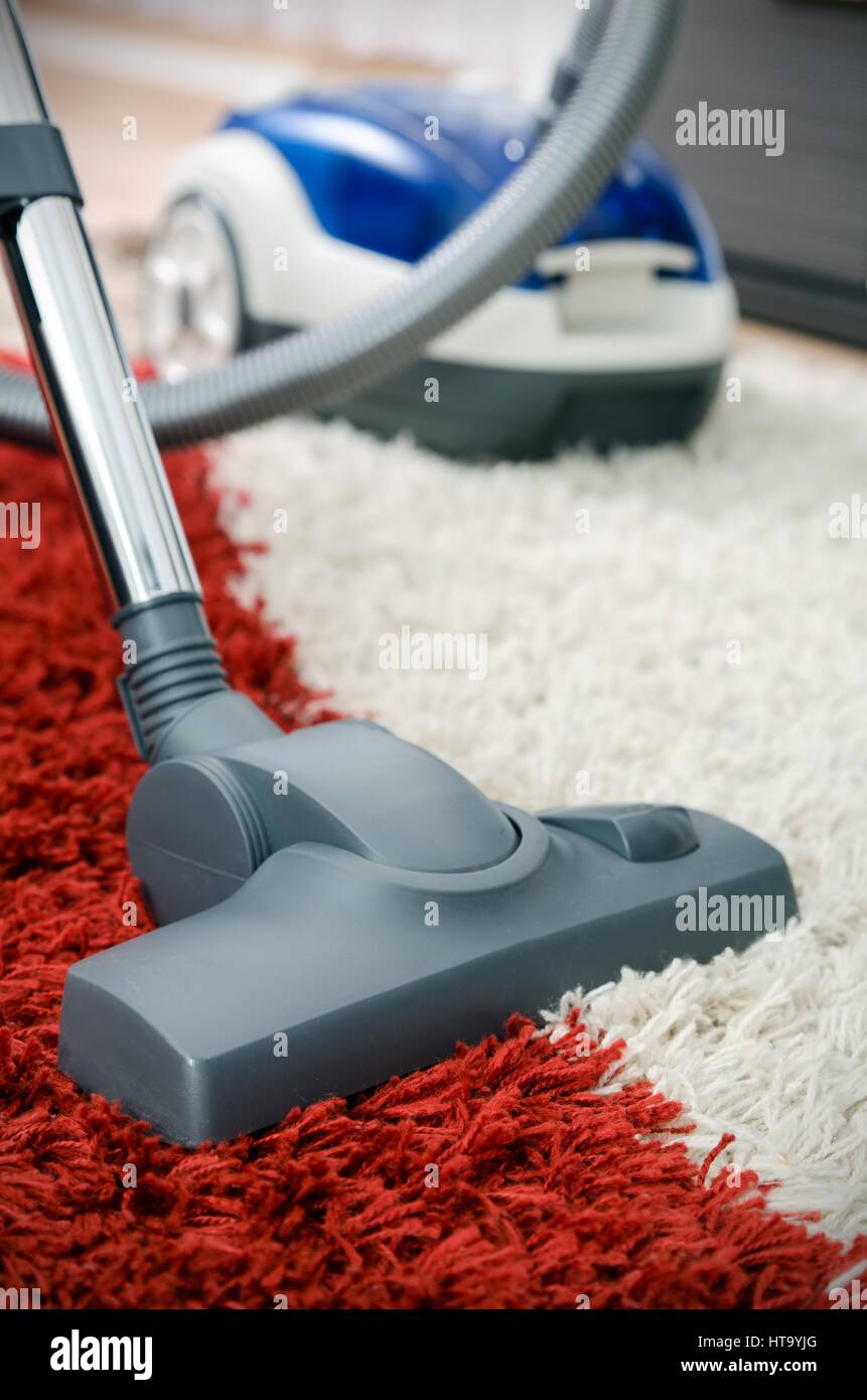 Blue vacuum cleaner on shaggy carpet inside room close up Stock Photo