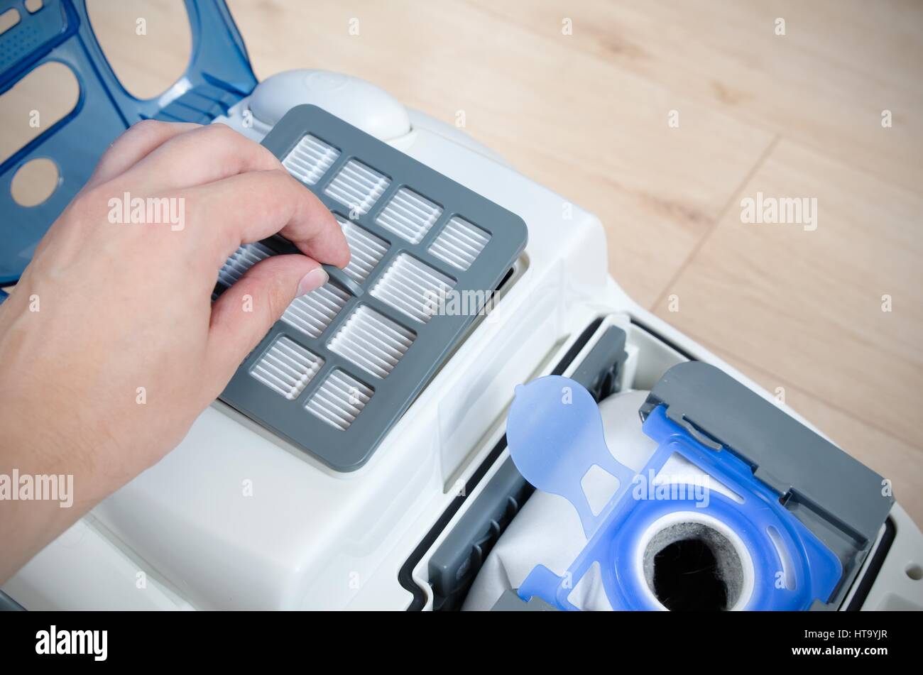 Hand replacing the air filter in a modern vacuum cleaner Stock Photo